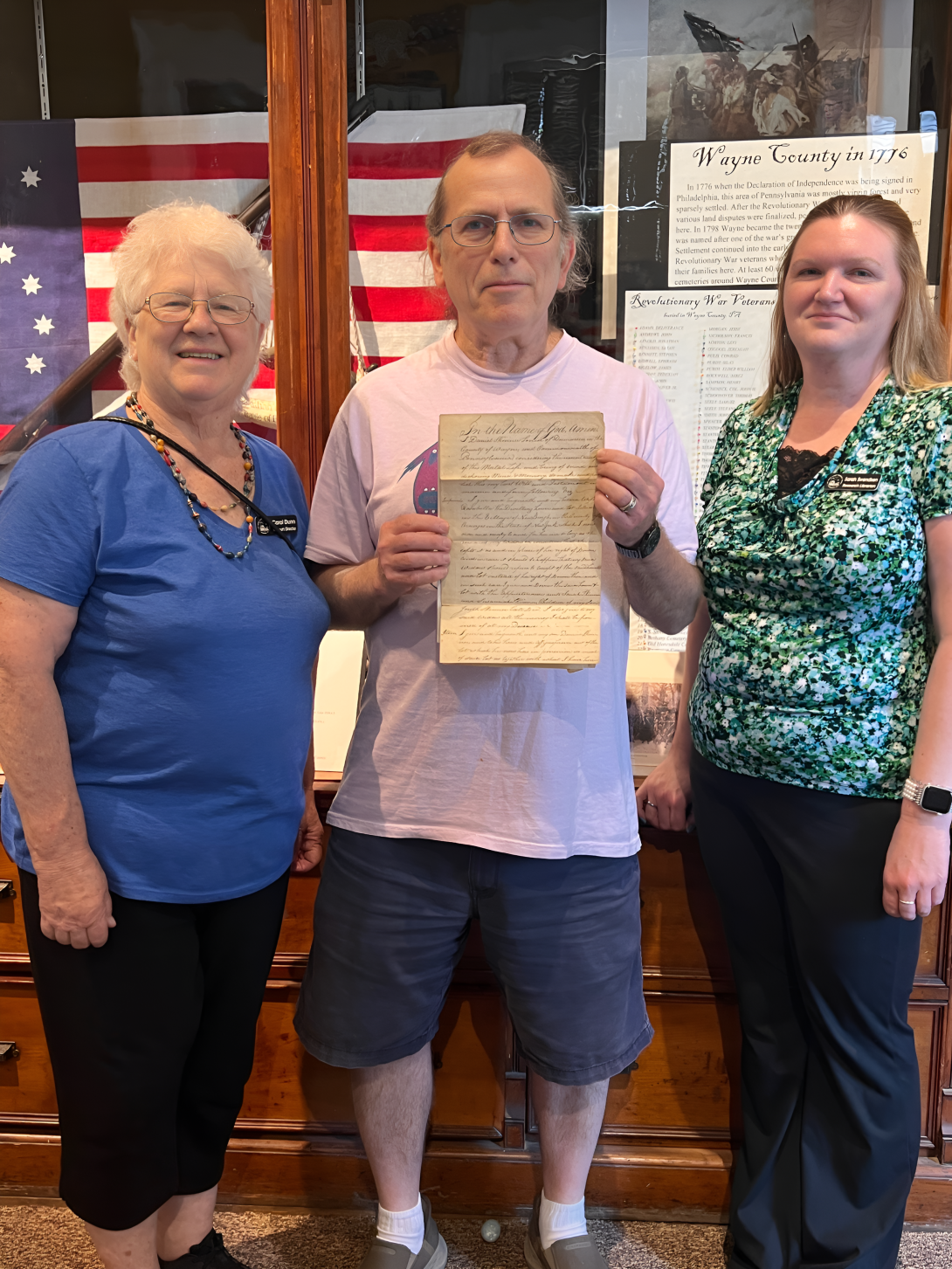 Carol Dunn (left) and Sarah Swendsen (right) with Tom Rue who holds the Skinner document.